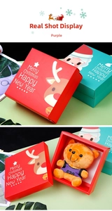 Detailed view of open Christmas gift box with reindeer patterns and a plush teddy bear
