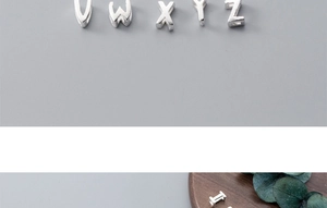 Detailed view of silver alphabet charms V W X Y Z on a wooden tray with greenery