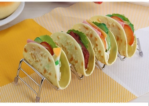 Polished stainless steel taco holder stand placed on a textured woven table mat
