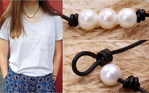 Dettaglio di tre perle d'acqua dolce bianche su collana in pelle nera con nodi