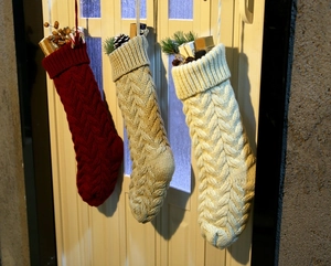 Close-up of three knitted Christmas stockings with cable patterns in red and cream colors