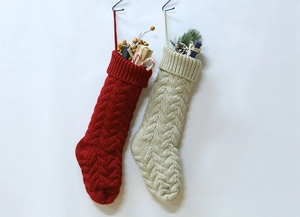 Detail of red and beige knitted Christmas stockings with cable patterns and decorations