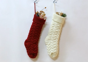 Detail view of large red and cream knitted Christmas stockings with holiday decorations