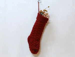 Detail view of red knitted Christmas stocking with candy canes and gift boxes