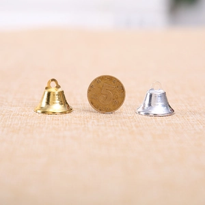 Pair of gold and silver small metal bells with a coin for size reference and scale
