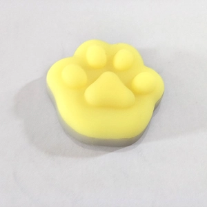Detailed view of yellow cat paw shaped squishy squeeze toy with grey base for stress relief