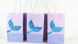 Detail view of purple paper gift bags with holographic laser mermaid tail design