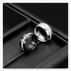 Detailed macro view of black and silver stainless steel rings with sparkling inlaid crystals