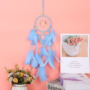 Detail of dream catcher wall decor with blue feathers, wooden beads and heart pendant