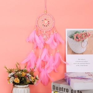Detailed view of pink handmade dream catcher with soft feathers and beads on a wall