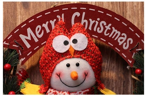 Close-up of knit snowman doll with Merry Christmas sign on festive holiday wreath