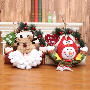 Christmas rattan wreath set with reindeer and snowman plush dolls on a cozy wooden background