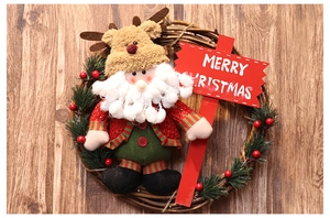 Detail of Christmas wreath with plush dolls and Merry Christmas sign on wood background