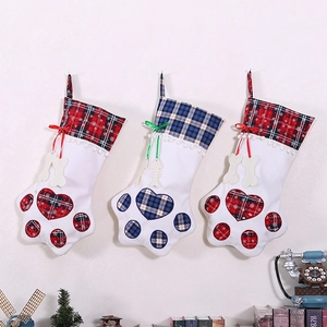 Three pet paw Christmas stockings in red and blue plaid hanging on a white wall decor
