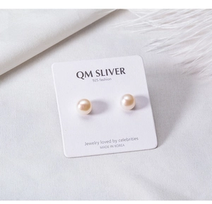 Macro shot of 925 sterling silver studs with round natural freshwater pearls on a display card