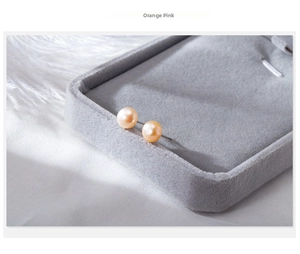 Macro shot of orange-pink natural freshwater pearl studs on a grey velvet jewelry tray