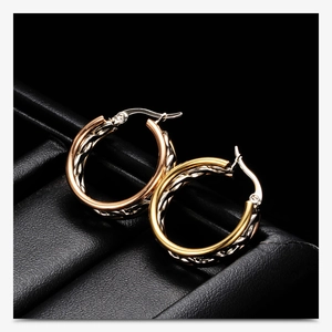 Macro shot of 25mm hollow textured tri-color earrings on a premium black leather stand