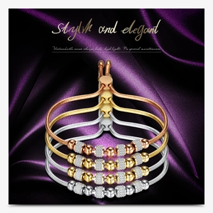 Detail of four stacked 6mm rhinestone ball bracelets in gold, silver, and rose gold