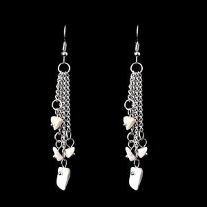 Macro detail of handmade bohemian silver tassel earrings with white natural crystal stones