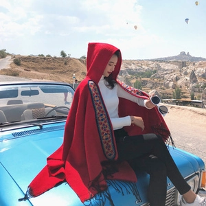 Detail of red hooded poncho scarf with ethnic embroidery and tassels in desert setting