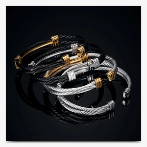 Macro shot of 10mm woven steel cable bracelets in black, silver, and gold stacked together