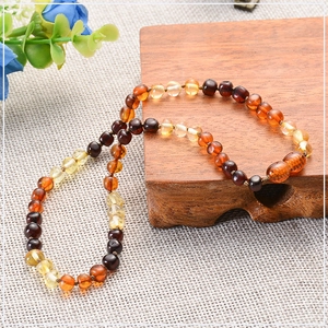 Macro shot of multi-colored natural amber beads necklace on rustic linen and wood background