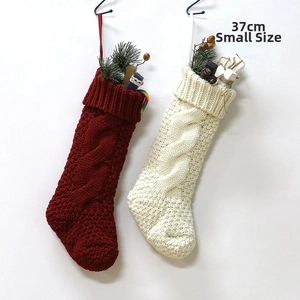 Detail of red and cream cable knit Christmas stockings with festive pine and gift fillings