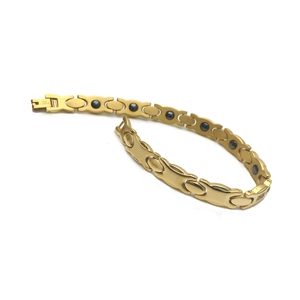 Détail d'un bracelet magnétique en acier inoxydable doré avec pierres noires et maillons X