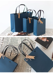 Close-up of deep blue paper gift bags with black handles and vintage thank you tags