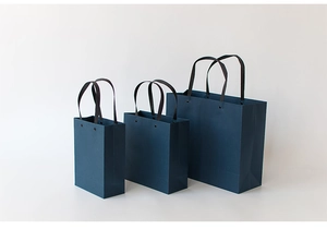 Three deep blue minimalist paper gift bags with black handles shown in various sizes