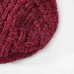 Detalle del tejido de trenzas gruesas en un gorro de invierno de chenilla color burdeos