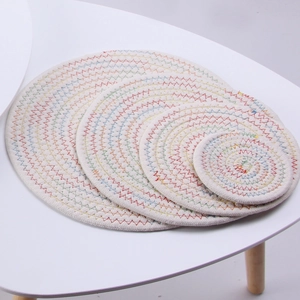 Detailed macro view of four round beige cotton woven mats with colorful stitching patterns