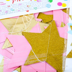 Detail of pink and gold glitter star garland decorations in transparent packaging