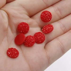 Detailed view of 10mm red resin druzy cabochons in palm showing small scale and flat back