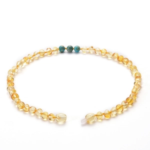 Collier en ambre pour bébé avec perles de turquoise et améthyste sur fond blanc