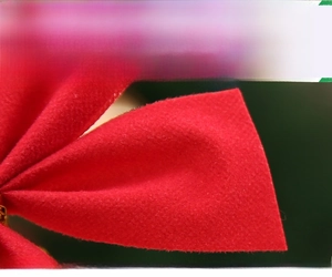 Vue macro d'un nœud de Noël rouge floconné avec une texture douce sur fond vert flou