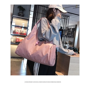 Model wearing a large pink waterproof nylon travel bag with side zipper pocket detail