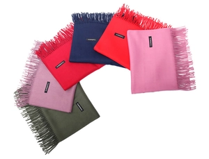 Close-up of multi-color cashmere scarves with elegant tassels and branded woven labels