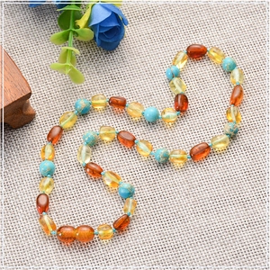 Dettaglio di una collana per neonati con ambra baltica naturale e perle turchesi