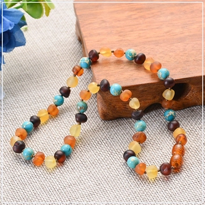 Detailed view of handmade amber and turquoise baby beads on rustic wood and woven fabric
