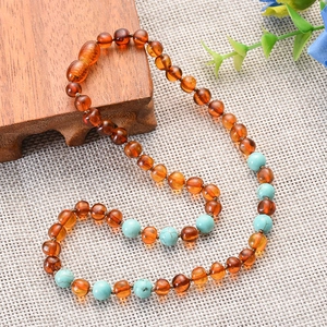 Baltic amber and turquoise teething necklace for babies in a natural S-curve layout