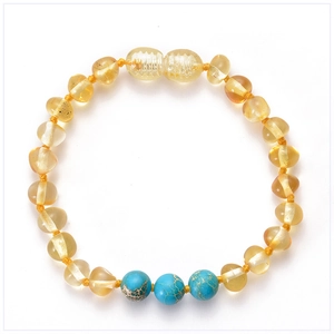 Detail of handcrafted Baltic amber baby bracelet with turquoise beads on white background