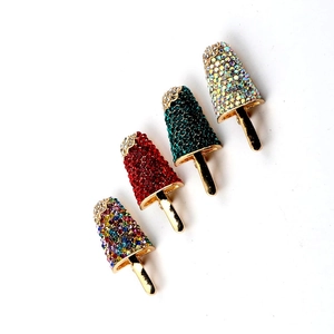 Detailed view of colorful rhinestone-encrusted popsicle brooches in gold setting