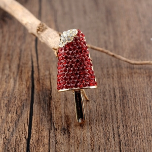 Macro shot of a red rhinestone popsicle brooch with a golden metal base on wood