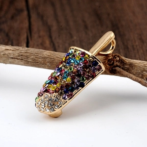 Macro shot of a golden ice cream brooch with colorful rhinestones on a wooden branch