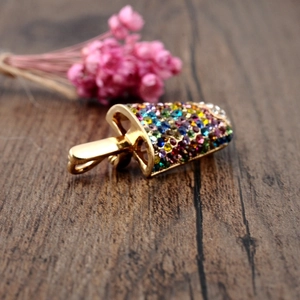 Macro shot of gold popsicle brooch with colorful rhinestones on a wooden background