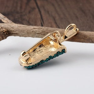 Gold ice cream brooch with blue-green rhinestones on a natural wooden branch background