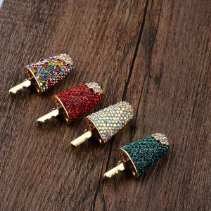 Sparkling crystal ice cream brooches in four colors set on a rustic wooden background