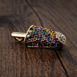 Detailed view of an ice cream brooch with colorful rhinestones on a wooden background