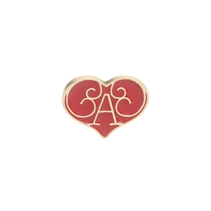 Macro shot of red enamel heart brooch with gold scrollwork and script lettering